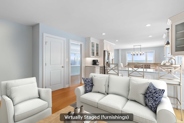 living room with sink, a chandelier, and light wood-type flooring