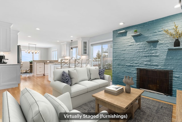 living room featuring plenty of natural light, a stone fireplace, and light hardwood / wood-style floors