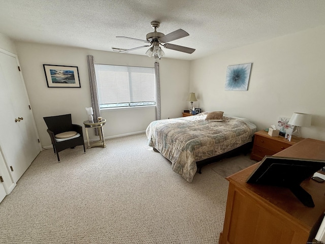 carpeted bedroom featuring ceiling fan and a textured ceiling