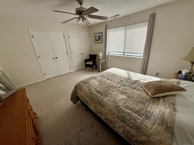 bedroom with multiple closets, ceiling fan, and a textured ceiling