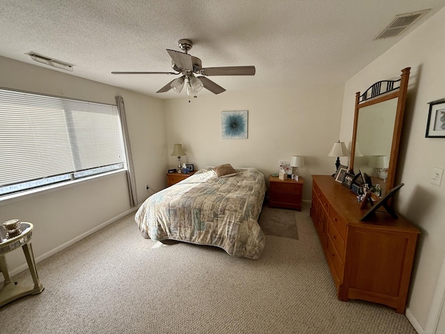 bedroom with ceiling fan, light colored carpet, and a textured ceiling