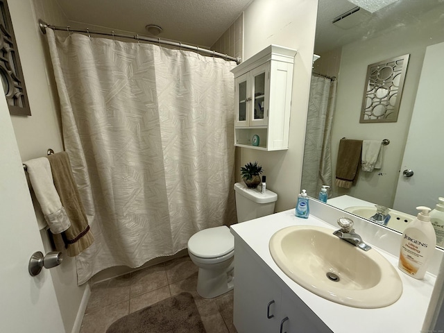 bathroom featuring tile patterned flooring, vanity, a textured ceiling, and toilet