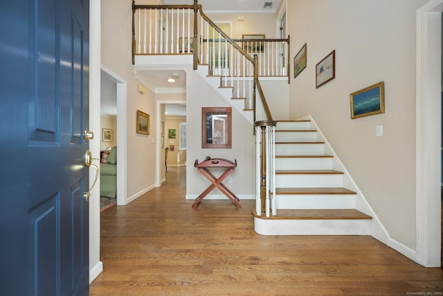 entrance foyer with a high ceiling, ornamental molding, and hardwood / wood-style floors