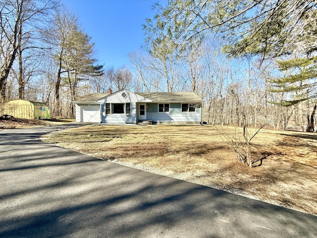 view of front of property with driveway, a chimney, and a garage