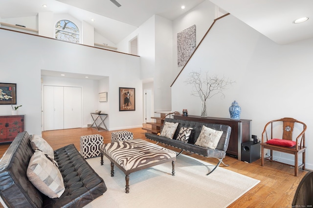 living area featuring high vaulted ceiling, recessed lighting, stairway, and wood finished floors