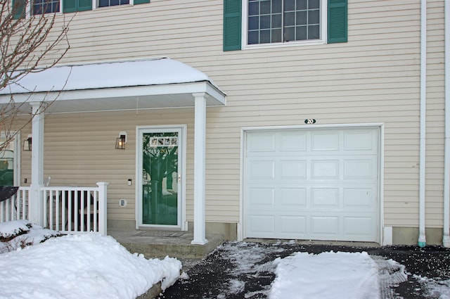 snow covered property entrance featuring a garage