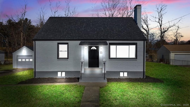 view of front facade with a garage, an outdoor structure, and a lawn