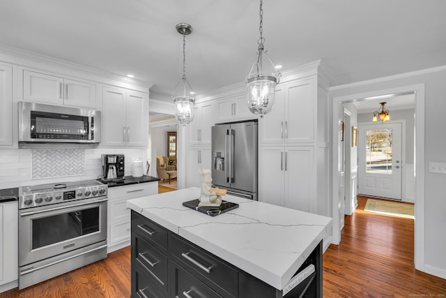 kitchen with white cabinets, a center island, hanging light fixtures, stainless steel appliances, and dark cabinetry