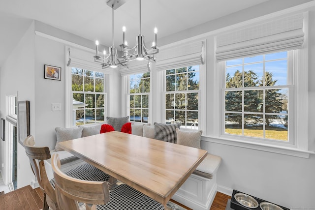 dining area with baseboards, wood finished floors, and a notable chandelier