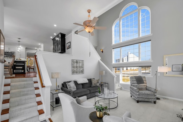 living room with a towering ceiling, stairway, and a ceiling fan