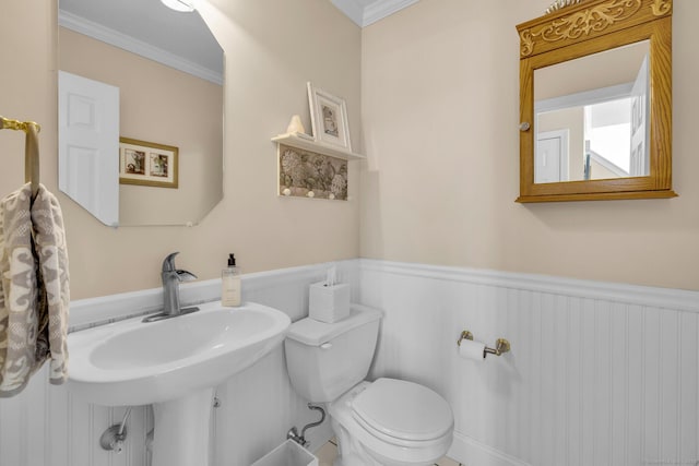 half bath with toilet, ornamental molding, and wainscoting