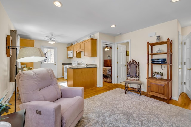 living room featuring ceiling fan, recessed lighting, baseboards, and light wood-style floors