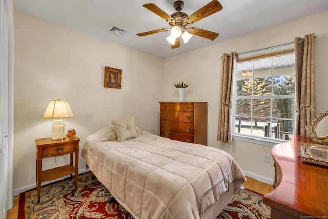 bedroom with visible vents, ceiling fan, baseboards, and wood finished floors