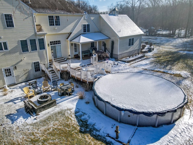 snow covered property featuring a deck and an outdoor fire pit