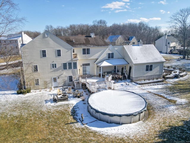 snow covered house featuring a deck, a chimney, and a residential view