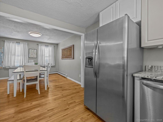 kitchen featuring stainless steel appliances, white cabinets, light stone counters, and light hardwood / wood-style flooring