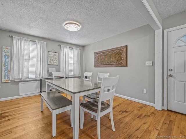 dining space featuring light hardwood / wood-style floors and a textured ceiling