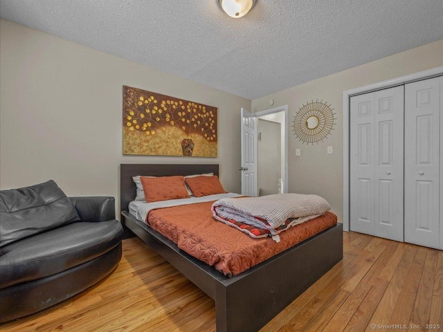 bedroom featuring a textured ceiling, light hardwood / wood-style floors, and a closet