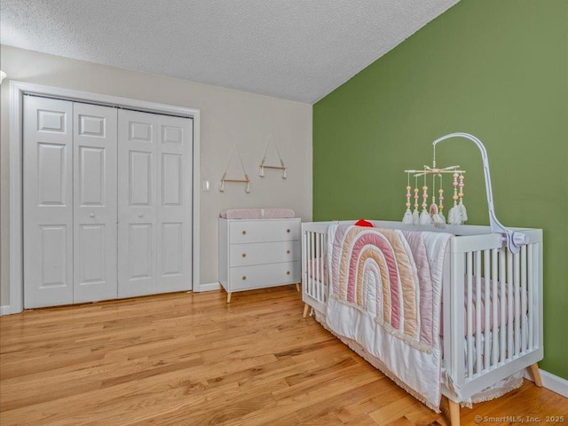 bedroom with a closet, a textured ceiling, and light wood-type flooring