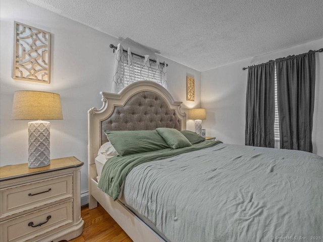 bedroom with light hardwood / wood-style flooring and a textured ceiling