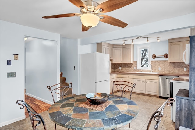 kitchen with tasteful backsplash, sink, white fridge, stainless steel dishwasher, and light tile patterned floors