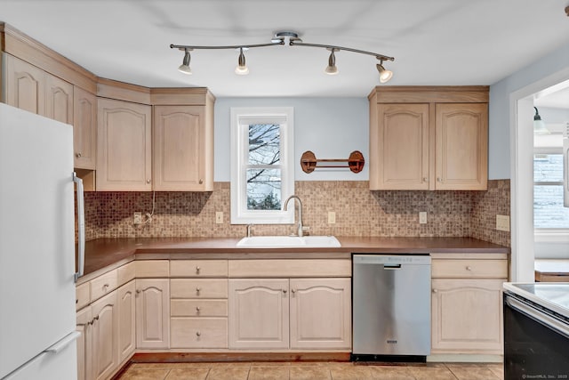 kitchen featuring a wealth of natural light, light brown cabinetry, sink, white fridge, and stainless steel dishwasher