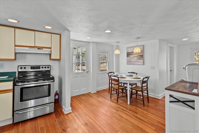 kitchen with electric stove, under cabinet range hood, cream cabinets, a textured ceiling, and light wood finished floors