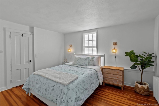 bedroom featuring radiator heating unit and wood finished floors