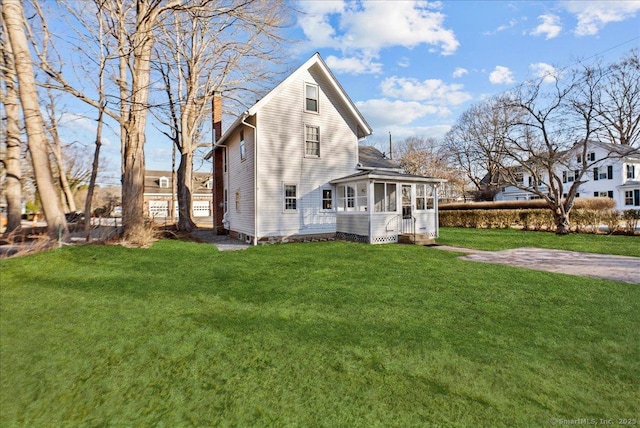 exterior space with a lawn, a chimney, and a sunroom