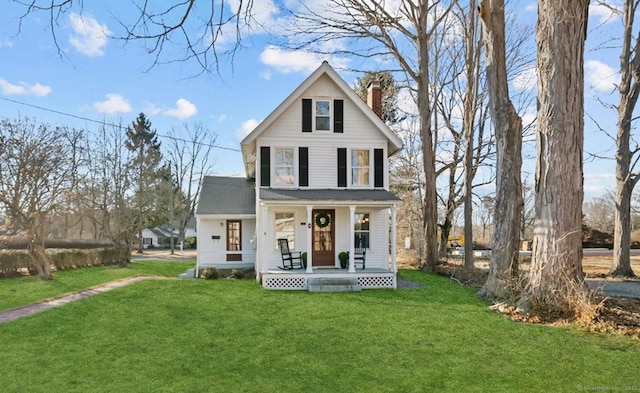 view of front facade featuring a front lawn, covered porch, and a chimney