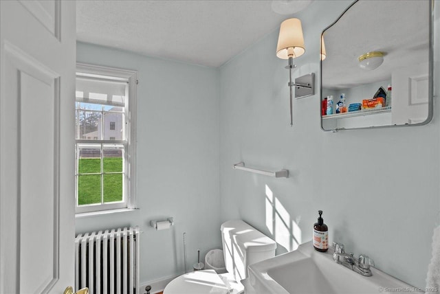 half bath with a sink, radiator, and toilet