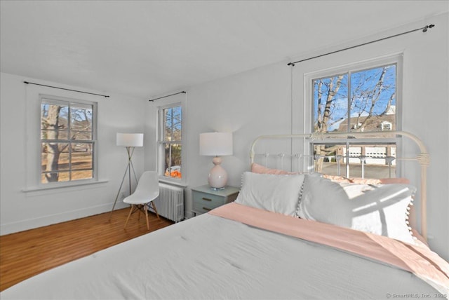 bedroom featuring radiator, wood finished floors, and baseboards