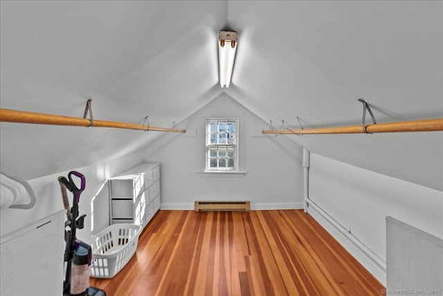 interior space with baseboards, light wood-type flooring, a baseboard heating unit, and lofted ceiling