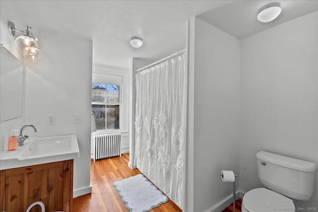 full bathroom with toilet, wood finished floors, radiator heating unit, a shower with shower curtain, and vanity