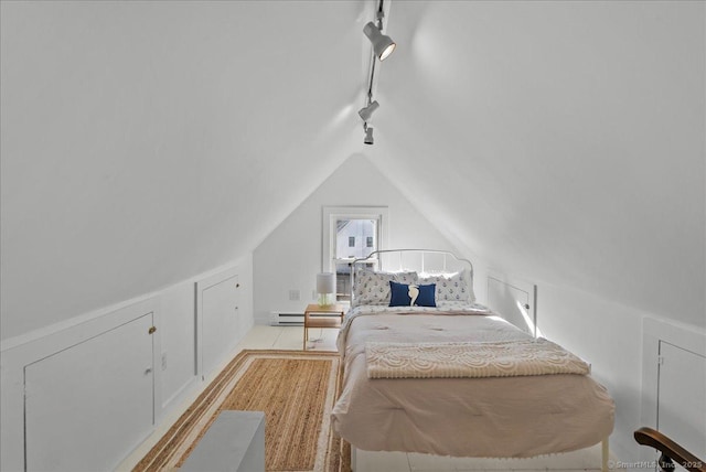 bedroom featuring a baseboard heating unit, lofted ceiling, and rail lighting