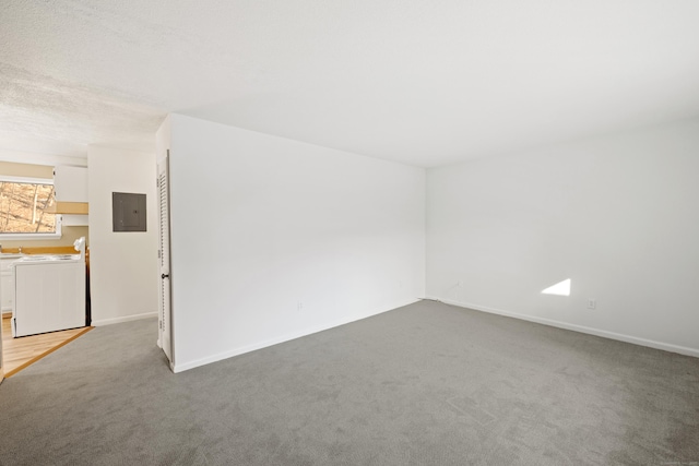 carpeted empty room featuring a textured ceiling, electric panel, and washer and clothes dryer