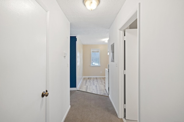 hallway with light carpet and a textured ceiling