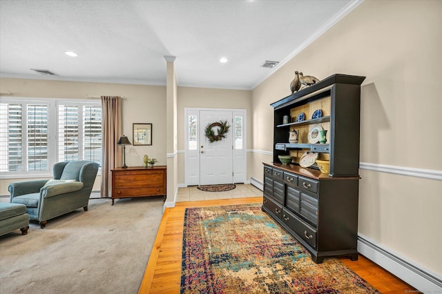 entrance foyer featuring decorative columns, a baseboard radiator, and crown molding