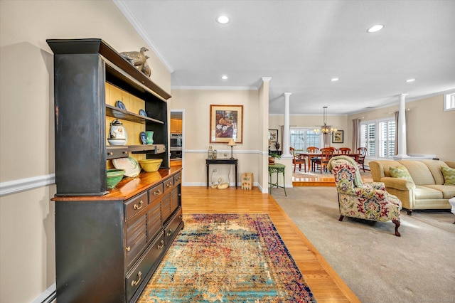 living room with ornamental molding, light hardwood / wood-style floors, baseboard heating, and ornate columns