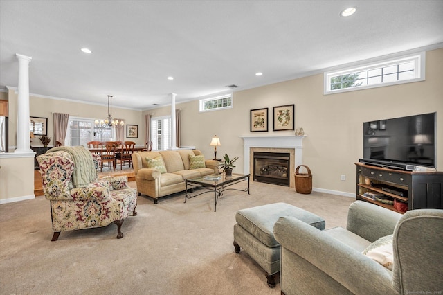 living room featuring crown molding, a tiled fireplace, decorative columns, a healthy amount of sunlight, and light carpet