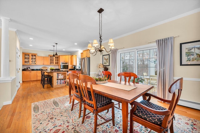 dining space featuring an inviting chandelier, crown molding, light hardwood / wood-style flooring, and ornate columns