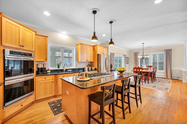 kitchen featuring sink, appliances with stainless steel finishes, dark stone countertops, hanging light fixtures, and a kitchen island