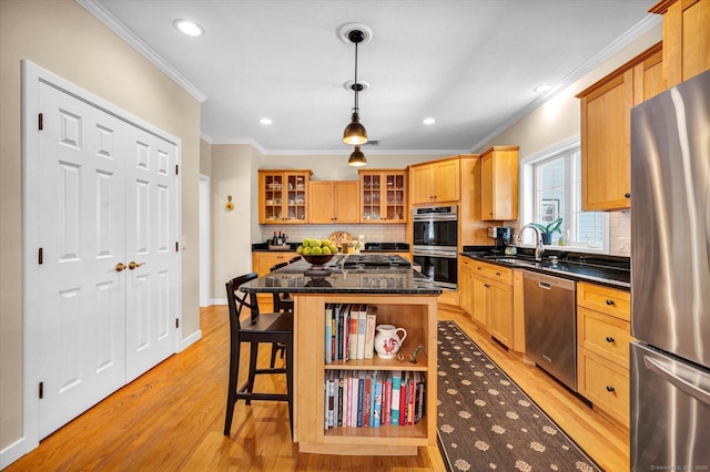 kitchen with pendant lighting, crown molding, light hardwood / wood-style flooring, appliances with stainless steel finishes, and a kitchen island