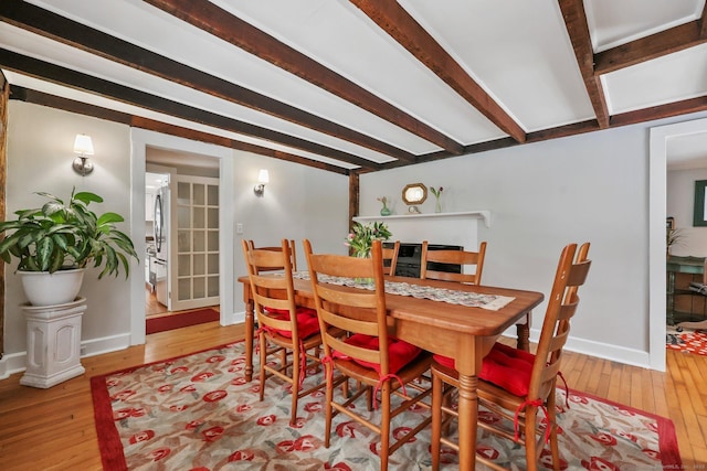 dining space featuring beamed ceiling and light hardwood / wood-style flooring