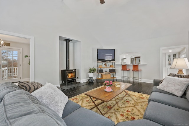 living room featuring a notable chandelier, dark wood-type flooring, and a wood stove