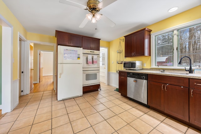 kitchen with sink, light tile patterned floors, ceiling fan, appliances with stainless steel finishes, and light stone counters