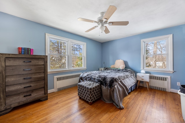 bedroom with multiple windows, radiator, and light hardwood / wood-style flooring