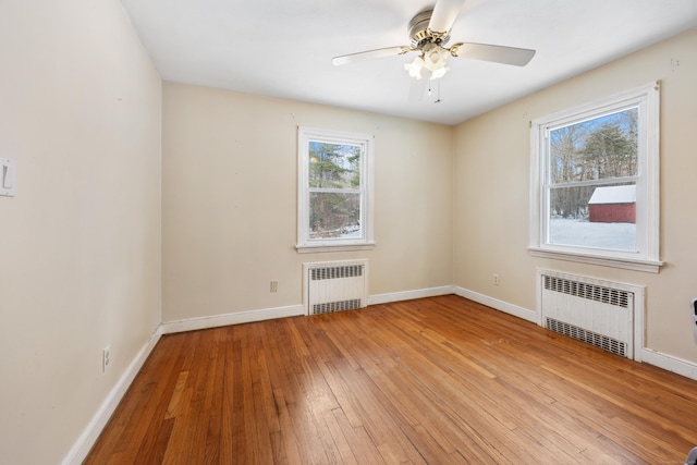 unfurnished room featuring radiator heating unit, ceiling fan, and light wood-type flooring