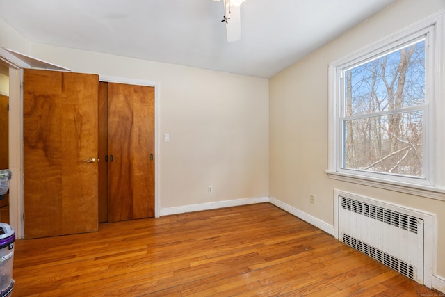 unfurnished bedroom featuring radiator and light hardwood / wood-style floors