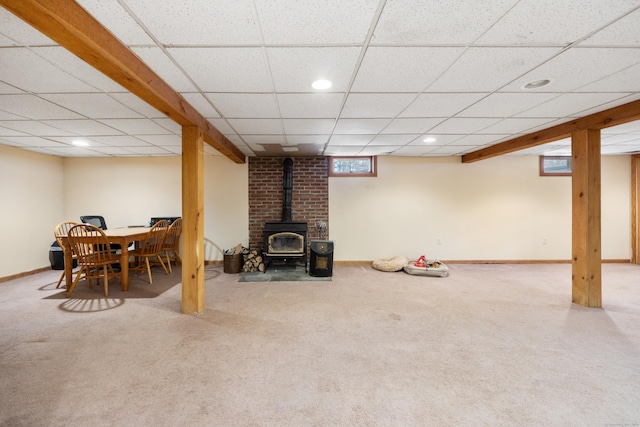 basement with a paneled ceiling, carpet, and a wood stove